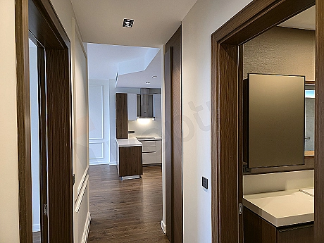 Interior of a modern apartment corridor with wooden floors and white walls.