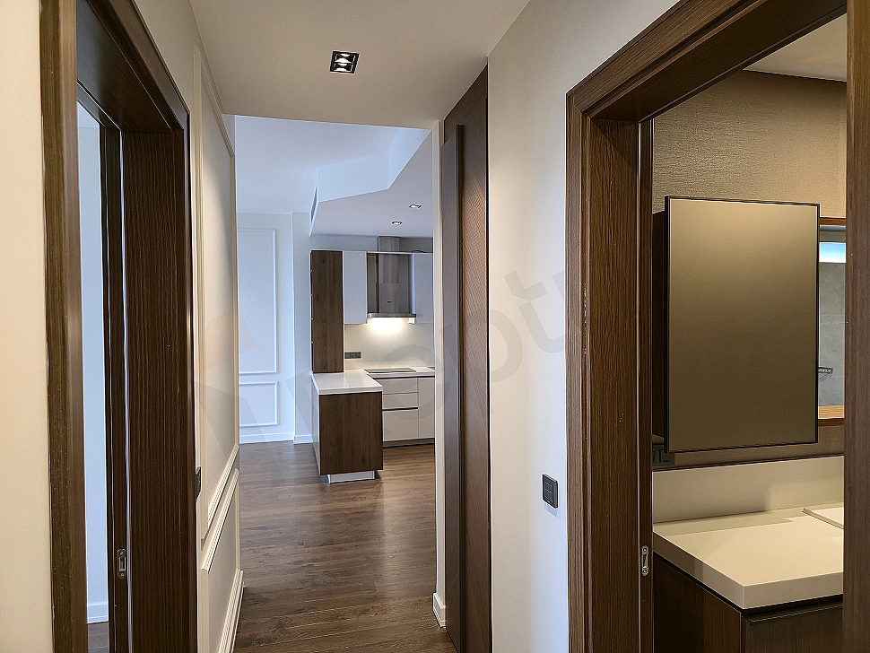 Interior of a modern apartment corridor with wooden floors and white walls.