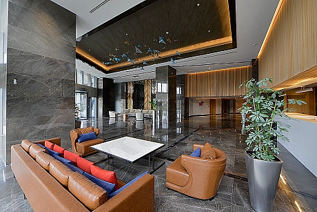 Bright and spacious photo of a modern building entrance. Features plants, stylish lighting, and a reception area.