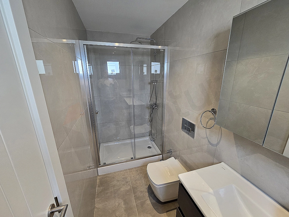 Modern designed bathroom interior. White tiles, shower cabin, sink and mirror details.