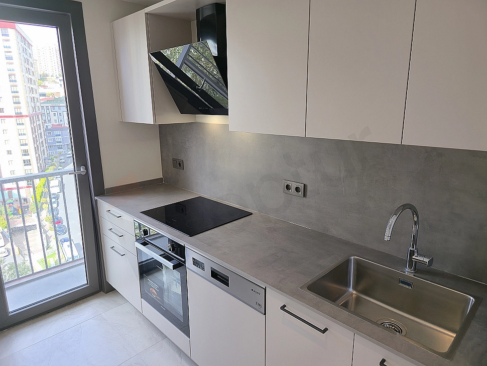 Bright kitchen with modern design, white cabinets, wooden countertops and built-in white appliances.