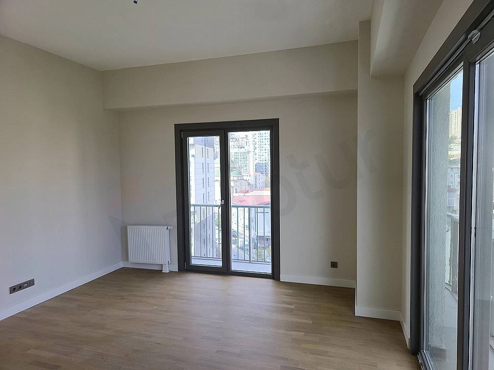Modern living room interior: Grey corner sofa, wooden TV unit, rug, and bright window.