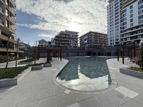 View of a large and clear swimming pool located in the garden of a modern residential project.