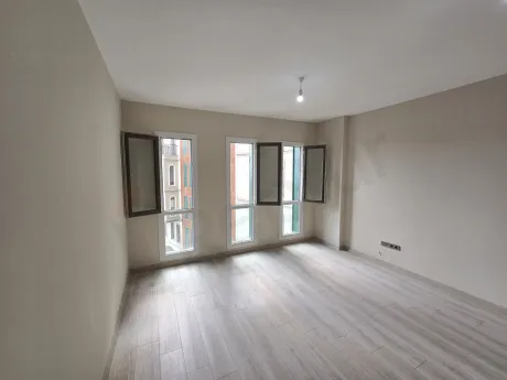 Modern and spacious empty studio apartment living room area with large windows.