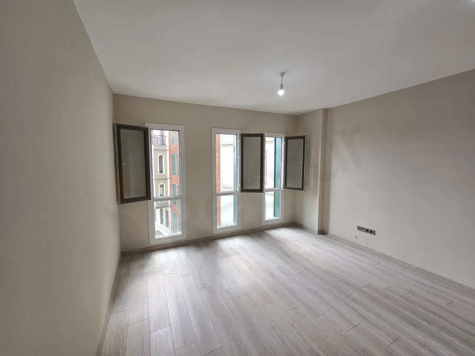 Modern and spacious empty studio apartment living room area with large windows.