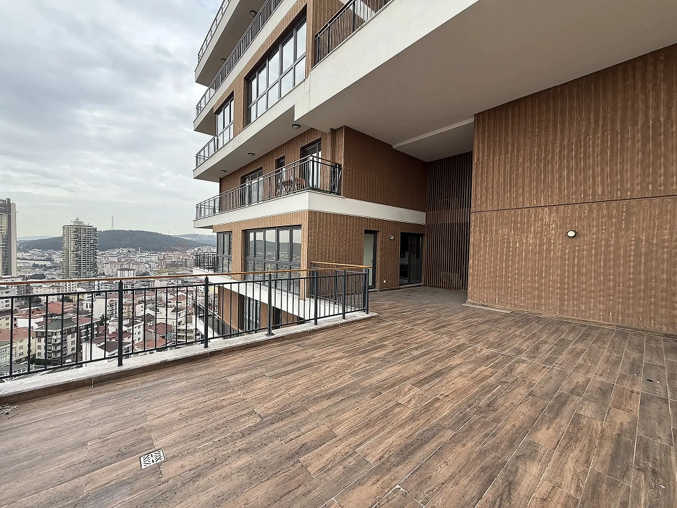 Spacious and open terrace area of a modern apartment with a dominant view of the city and forest.