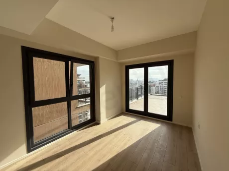 A bright and spacious bedroom area with large windows and modern flooring.