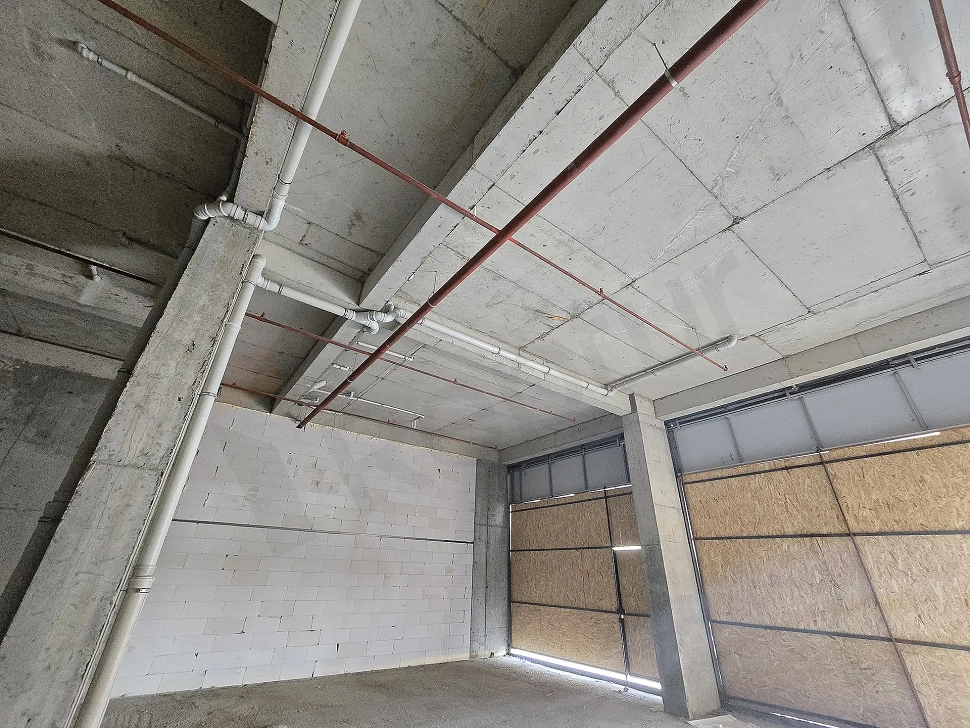 Spacious interior view of an unfinished 306 sqm shell and core shop for sale in Pendik, Istanbul with concrete structure and columns.