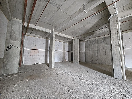 Unfinished shell-and-core interior of a spacious commercial shop or store.