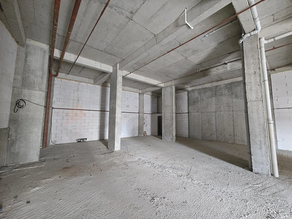 Unfinished shell-and-core interior of a spacious commercial shop or store.