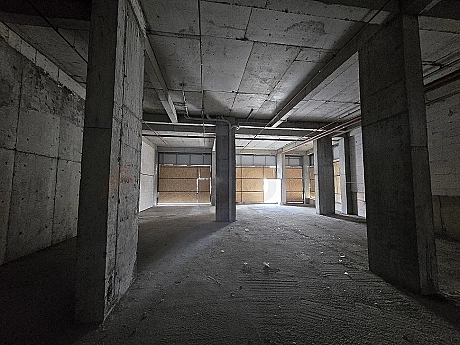 Interior view of a spacious unfinished shop with shell and core concrete structure.