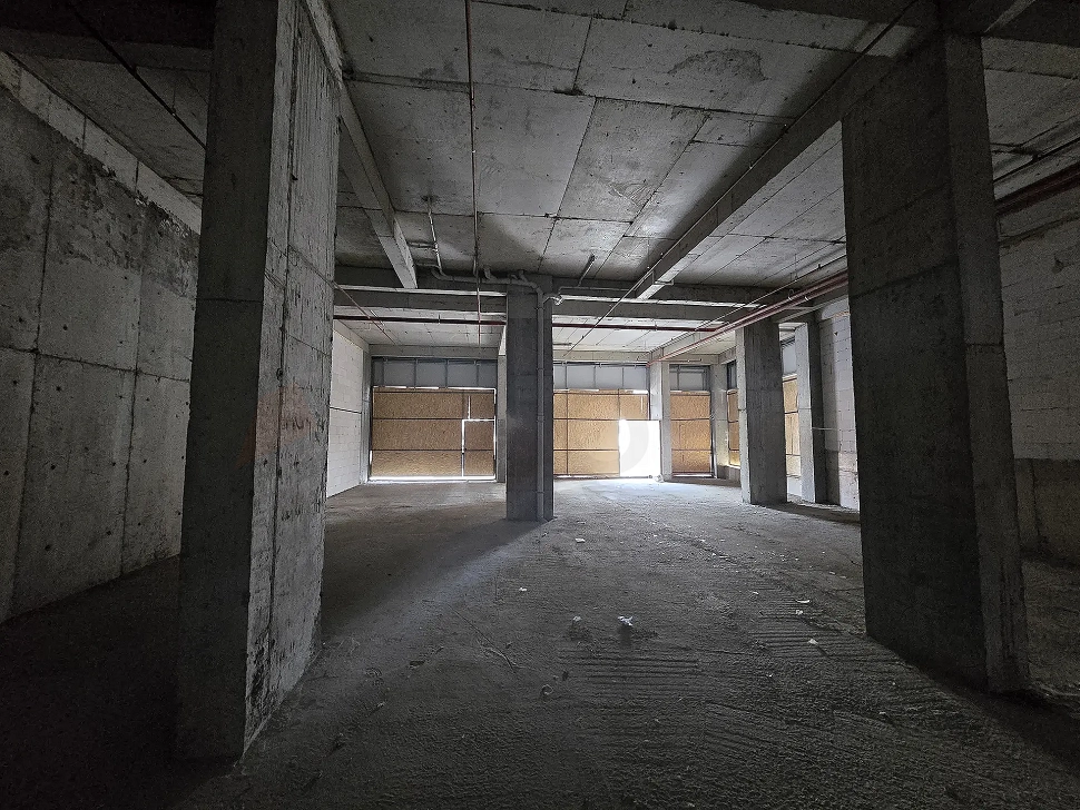 Interior view of a spacious unfinished shop with shell and core concrete structure.