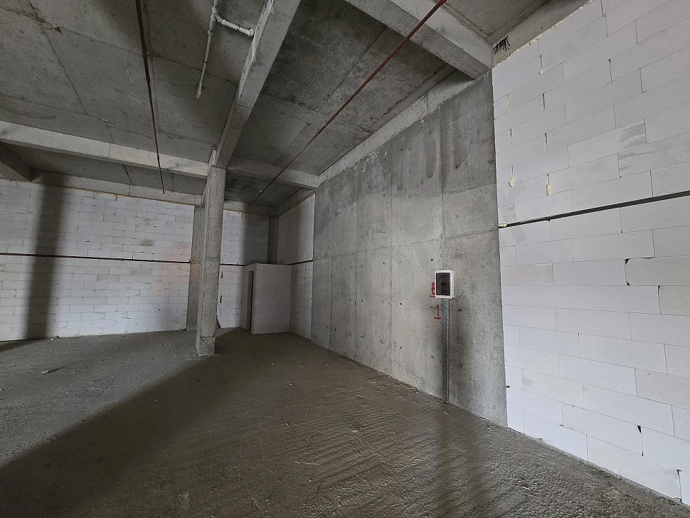 Interior view of a large unfinished commercial shop space with concrete structure