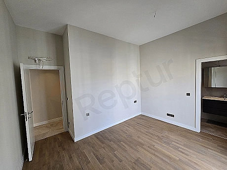 Modern bedroom interior: double bed, nightstands, lamps, rug, and minimalist design.