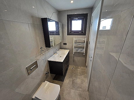 Modern designed, bright and spacious bathroom interior. White ceramic sink, large mirror and stylish fixtures.