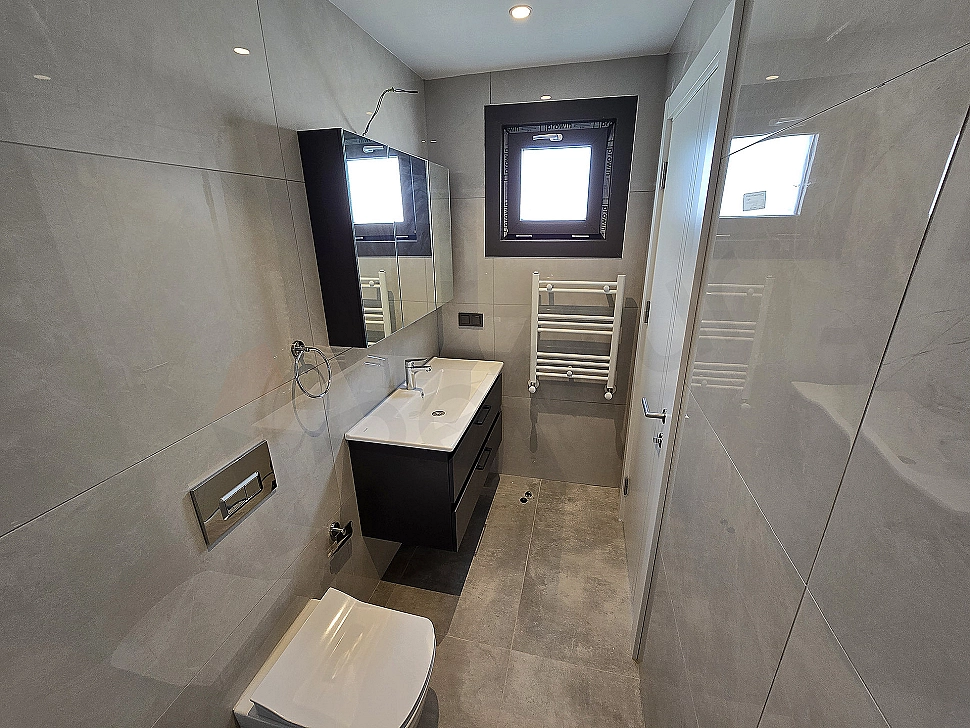 Modern designed, bright and spacious bathroom interior. White ceramic sink, large mirror and stylish fixtures.