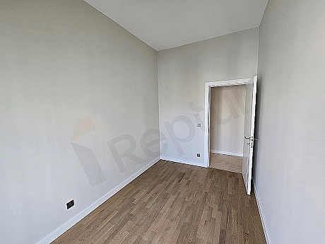 Interior view of a modernly designed bedroom. Features a double bed, bedside tables, lamps, and minimalist decor details.