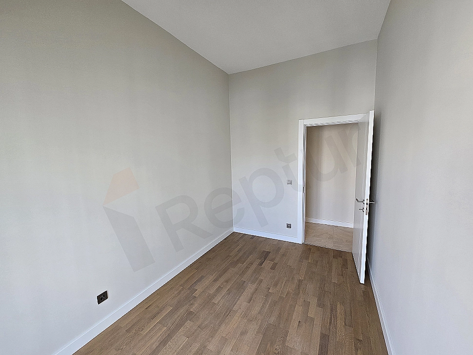 Interior view of a modernly designed bedroom. Features a double bed, bedside tables, lamps, and minimalist decor details.