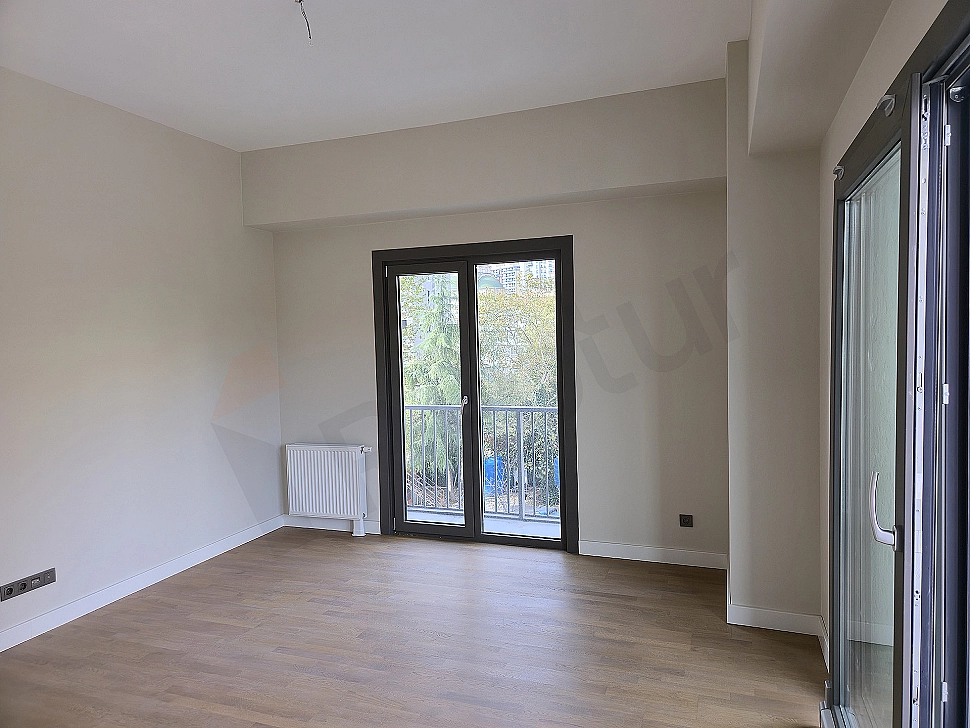 Modern living room interior: Gray corner sofa, wooden coffee table, white walls, and natural light.