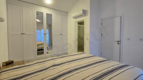 Image of a spacious and bright bedroom furnished with modern furniture.