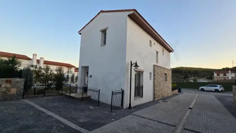 Exterior shot of a modern 3+1 villa with garden and large windows in a contemporary residential complex.