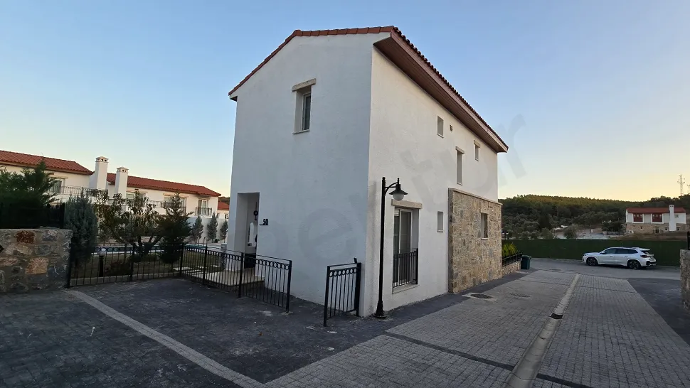 Exterior shot of a modern 3+1 villa with garden and large windows in a contemporary residential complex.