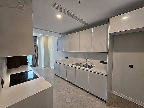 Bright and spacious kitchen with modern white cabinets, wooden countertop and built-in appliances.