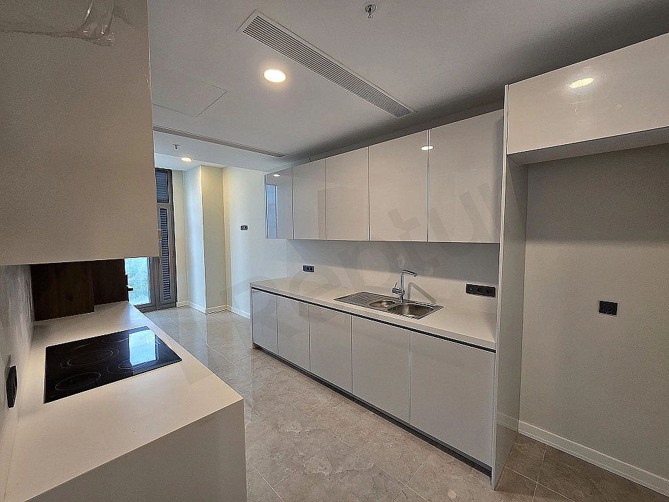 Bright and spacious kitchen with modern white cabinets, wooden countertop and built-in appliances.