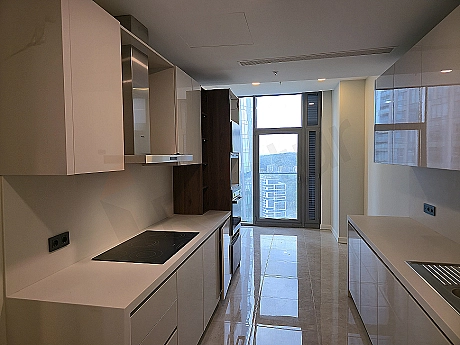 Spacious kitchen with modern white cabinets, wooden countertop, built-in oven, and hob.