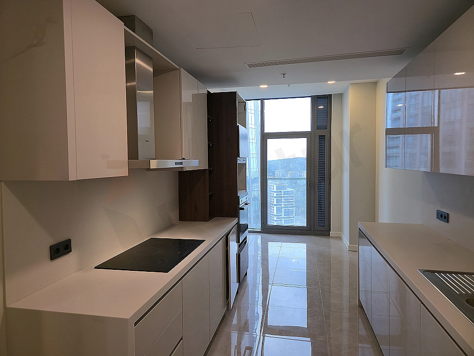 Spacious kitchen with modern white cabinets, wooden countertop, built-in oven, and hob.