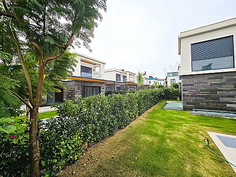Modern hotel garden in Bodrum with palm trees and green landscaping.