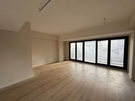 A spacious and bright living room with modern design and large windows letting in natural light.