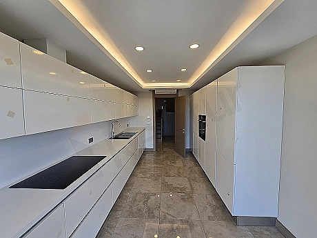Bright and spacious kitchen with modern design, white cabinets and built-in appliances.